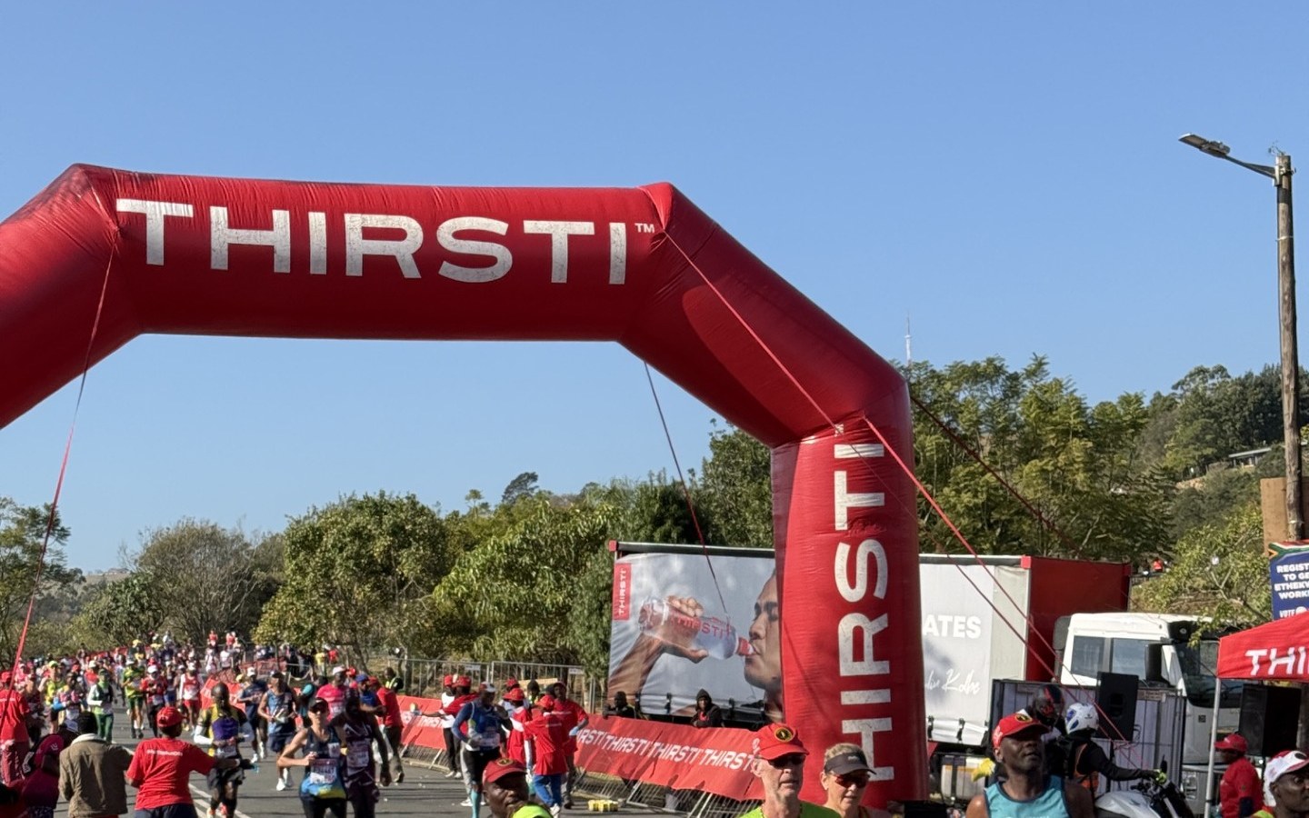 Runners passing under the THIRSTI arch at halfway, Comrades Marathon